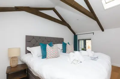 a bedroom with a large white bed with blue pillows at Carines Barns - Pen in Newquay