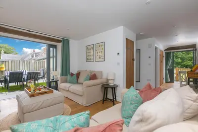 a living room with white furniture and a large window at Carines Barns - Pen in Newquay