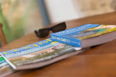 two books sitting on a table with a pair of glasses at Carines Barns - Wesley Barn in Newquay