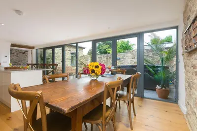 a dining room with a wooden table and chairs at Carines Barns - Wesley Barn in Newquay