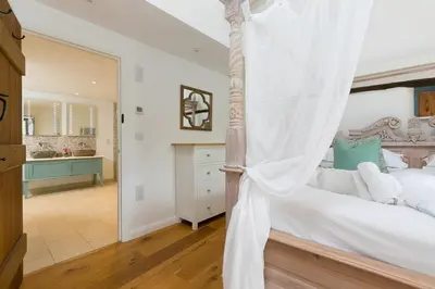 a bedroom with a canopy bed and a bathroom at Carines Barns - Wesley Barn in Newquay