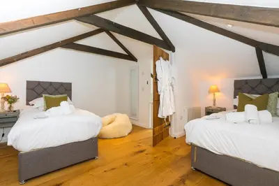 two beds in a room with wooden floors at Carines Barns - Wesley Barn in Newquay