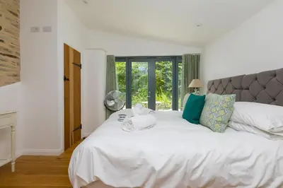 a bedroom with a large white bed and a window at Carines Barns - Wesley Barn in Newquay