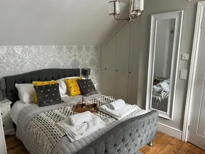 a bedroom with a bed with towels and a mirror at The Captain's House in Looe