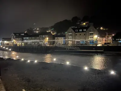 a city at night with lights on the water at The Captain's House in Looe