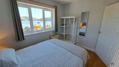 a bedroom with a bed and a large window at Polmaro in Saint Mawes