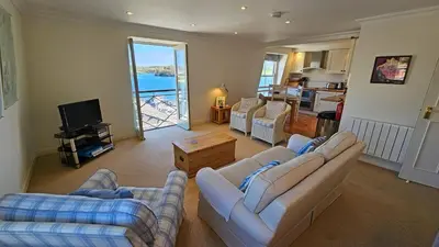 a living room with two couches and a kitchen at Pennant in Saint Mawes