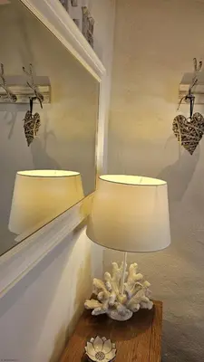 a lamp on a table next to a mirror at Beach Hill Cottage in Portloe