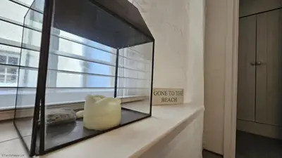 a mirror sitting on a shelf next to a window at Beach Hill Cottage in Portloe
