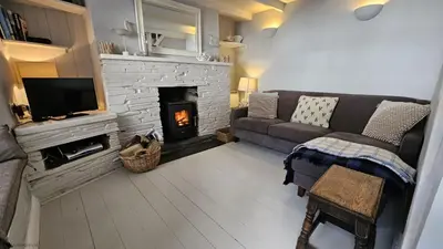 a living room with a couch and a fireplace at Beach Hill Cottage in Portloe