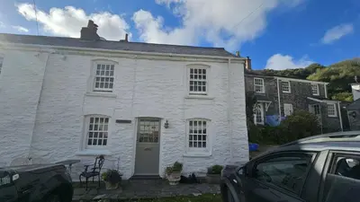 a white house with a car parked in front of it at Beach Hill Cottage in Portloe