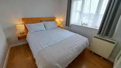 a bedroom with a bed and a window with two lamps at Pelyn in Saint Mawes