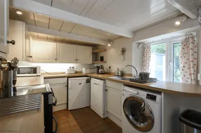 a kitchen with white cabinets and a washer in it at April Cottage in Saint Just in Roseland
