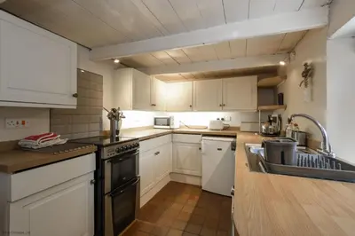 a kitchen with white cabinets and a black stove top oven at April Cottage in Saint Just in Roseland