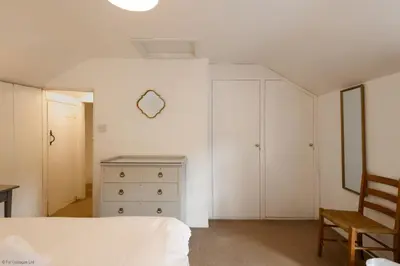 a bedroom with a bed and a dresser and a chair at April Cottage in Saint Just in Roseland