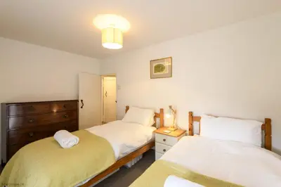 a bedroom with two beds and a dresser at April Cottage in Saint Just in Roseland