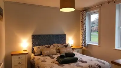 a bedroom with a bed with two lamps and a window at Valley View Lodges in Liskeard