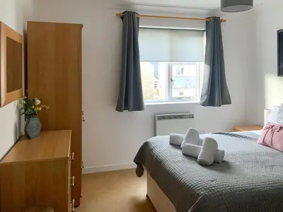 a bedroom with a bed with blue curtains and a window at Stream Side in Budock Water