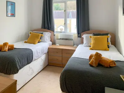a bedroom with two beds with yellow pillows on them at Stream Side in Budock Water