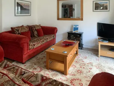 a living room with a red couch and a coffee table at Stream Side in Budock Water