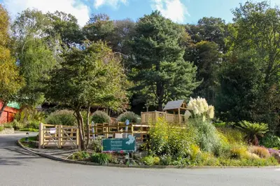 a garden with a wooden fence and a sign at Stream Side in Budock Water