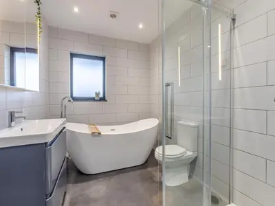 a bathroom with a tub and a toilet and a sink at Tregarden in Bude
