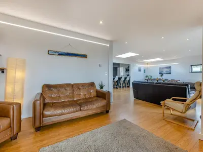 a living room with a leather couch and chairs at Tregarden in Bude