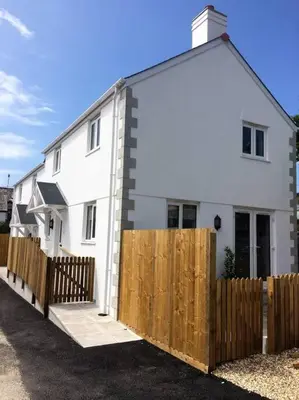 a white house with a wooden fence in front of it at Chy Bownder Cottage in Lostwithiel