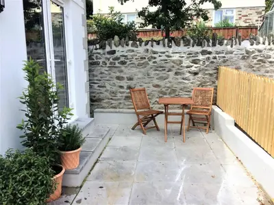a patio with two chairs and a wooden table at Chy Bownder Cottage in Lostwithiel