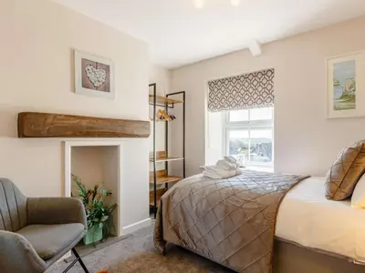 a bedroom with a bed and a chair and a window at Bells Cottage - Explore Cornwall by rail in St Austell
