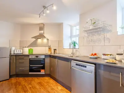 a large kitchen with stainless steel appliances and wood floors at Bells Cottage - Explore Cornwall by rail in St Austell