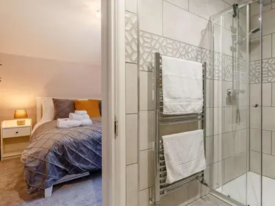 a bedroom with a bed and a glass shower at Bells Cottage - Explore Cornwall by rail in St Austell