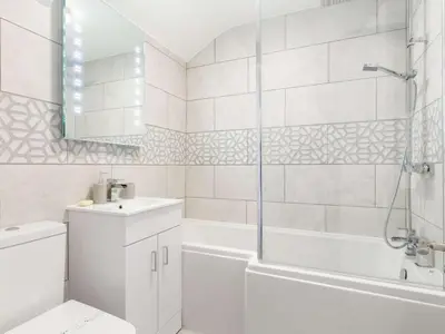 a white bathroom with a tub and a toilet and a sink at Bells Cottage - Explore Cornwall by rail in St Austell
