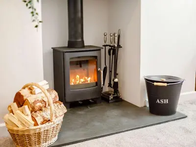 a fireplace in a room with a basket and a trash can at Bells Cottage - Explore Cornwall by rail in St Austell