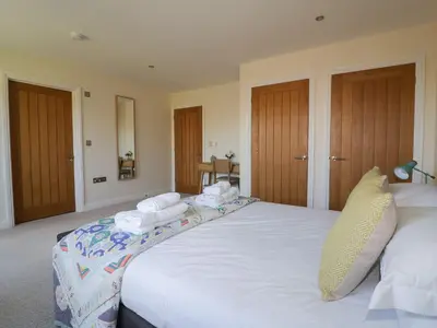 a bedroom with a large white bed with towels on it at Lower Mellan Barn in Helston