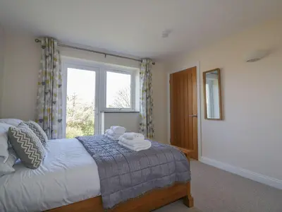 a bedroom with a bed and a large window at Lower Mellan Barn in Helston