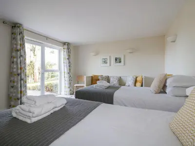 a bedroom with two beds and a window at Lower Mellan Barn in Helston