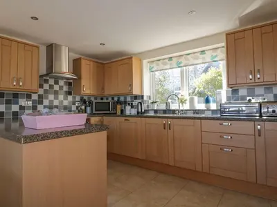 a large kitchen with wooden cabinets and a sink at Lower Mellan Barn in Helston