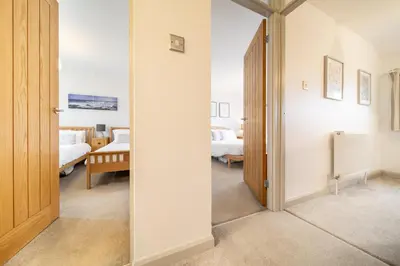 a hallway with a mirror and a room with two beds at Hebaska~Watergate Bay~3 Bedroom in Porth
