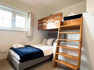 a bedroom with a bunk bed and a ladder at Hebaska~Watergate Bay~3 Bedroom in Porth