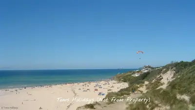 a group of people on a beach flying a kite at C35 Le Grace, Riviere Towans in Hayle