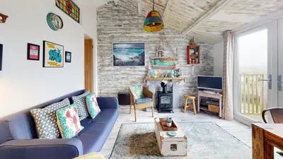 a living room with a blue couch and a fireplace at E41 Silver Mist, Riviere Towans in Hayle