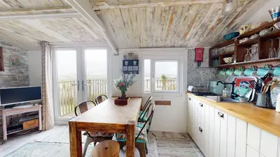 a kitchen with a wooden table and chairs in a room at E41 Silver Mist, Riviere Towans in Hayle