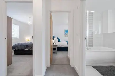 a bathroom with a tub and a bedroom with a bed at Modern House nr Gwithian Beach & St Ives in Tuckingmill