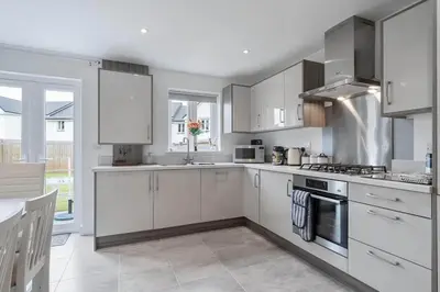 a kitchen with white cabinets and a stove top oven at Modern House nr Gwithian Beach & St Ives in Tuckingmill