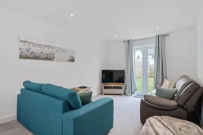 a living room with a blue couch and a chair at Modern House nr Gwithian Beach & St Ives in Tuckingmill