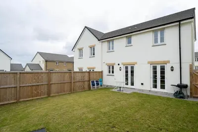a white house with a fence and a yard at Modern House nr Gwithian Beach & St Ives in Tuckingmill