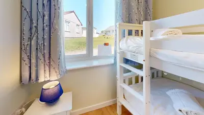 a bedroom with two bunk beds and a window at G07 Tweenbanx, Riviere Towans in Hayle