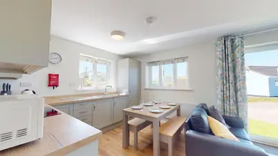 a kitchen and living room with a couch and a table at G07 Tweenbanx, Riviere Towans in Hayle