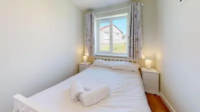 a small bedroom with a white bed and a window at G07 Tweenbanx, Riviere Towans in Hayle